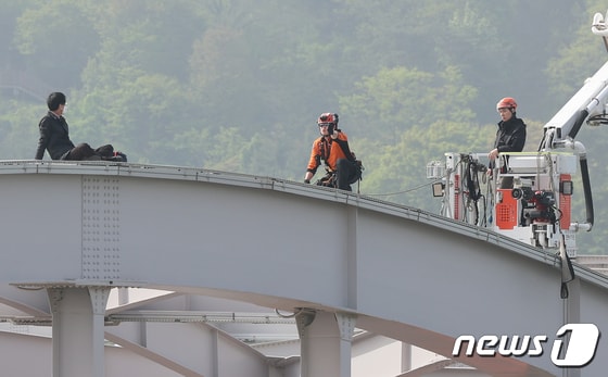 17일 오전 서울 한강대교 노량진 방면에서 교량 위에 올라가 소동을 벌이고 있는 신원을 알 수 없는 남성을 현장에 출동한 소방대원들이 설득하고 있다. 2024.4.17/뉴스1 © News1 김도우 기자