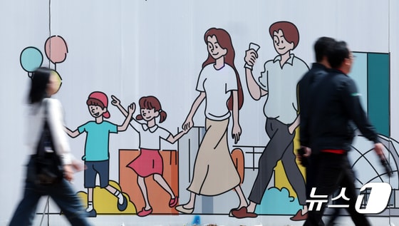 지난 2월 출생아 수가 지난해 같은 달보다 3.3% 줄어들며 처음으로 1만 명대로 내려앉은 가운데 24일 오후 서울 도심의 공사장 가림막에 그려진 행복한 가족 그림 앞으로 시민이 지나고 있다. 2024.4.24/뉴스1 © News1 박정호 기자