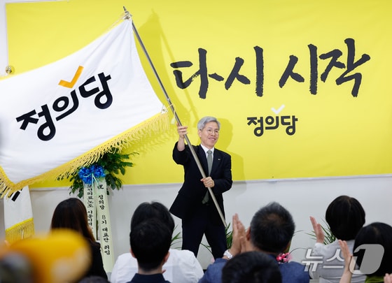 권영국 정의당 신임 대표가 28일 서울 여의도 국회에서 열린 정의당 7·8기 지도부 이취임식에서 당 깃발을 흔들고 있다. 2024.5.28/뉴스1 © News1 안은나 기자