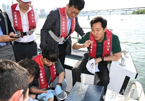 오세훈 서울시장이 '제1회 쉬엄쉬엄 한강 3종 축제'에 앞서 29일 오후 광진구 뚝섬한강공원 일대를 찾아, 한강 수질 검사를 위해 시료를 채취한 보건환경연구원 관계자들과 대화를 나누고 있다.(서울시 제공)© 뉴스1