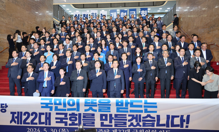 더불어민주당 이재명 대표와 박찬대 원내대표를 비롯한 22대 국회의원들이 30일 오후 서울 여의도 국회 중앙홀 계단에서 열린 의원총회에서 국기에 경례하고 있다. 연합뉴스