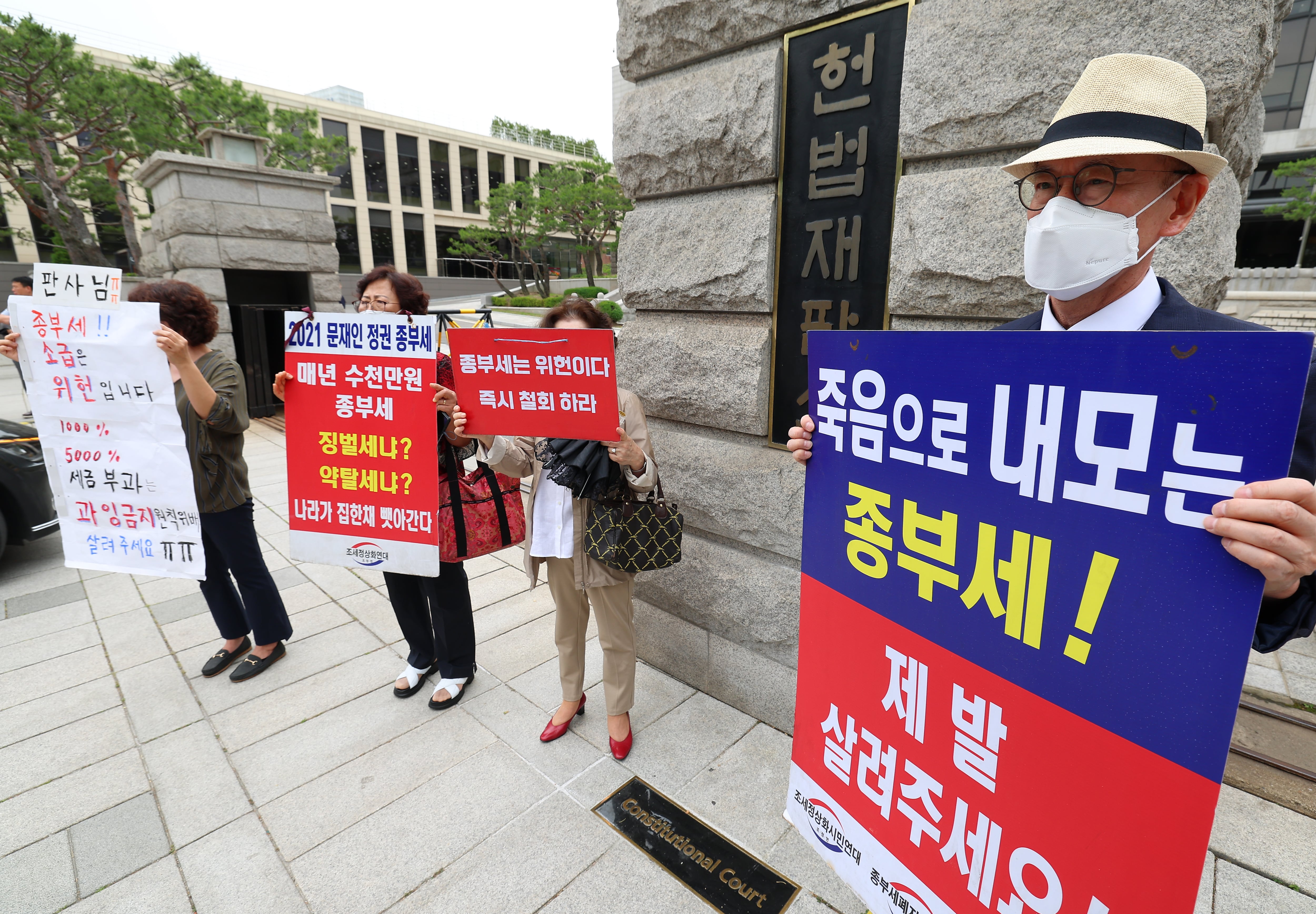 30일 오후 서울 종로구 헌법재판소 앞에서 시민들이 종부세 규탄 피켓을 들고 서 있다. /연합뉴스 제공