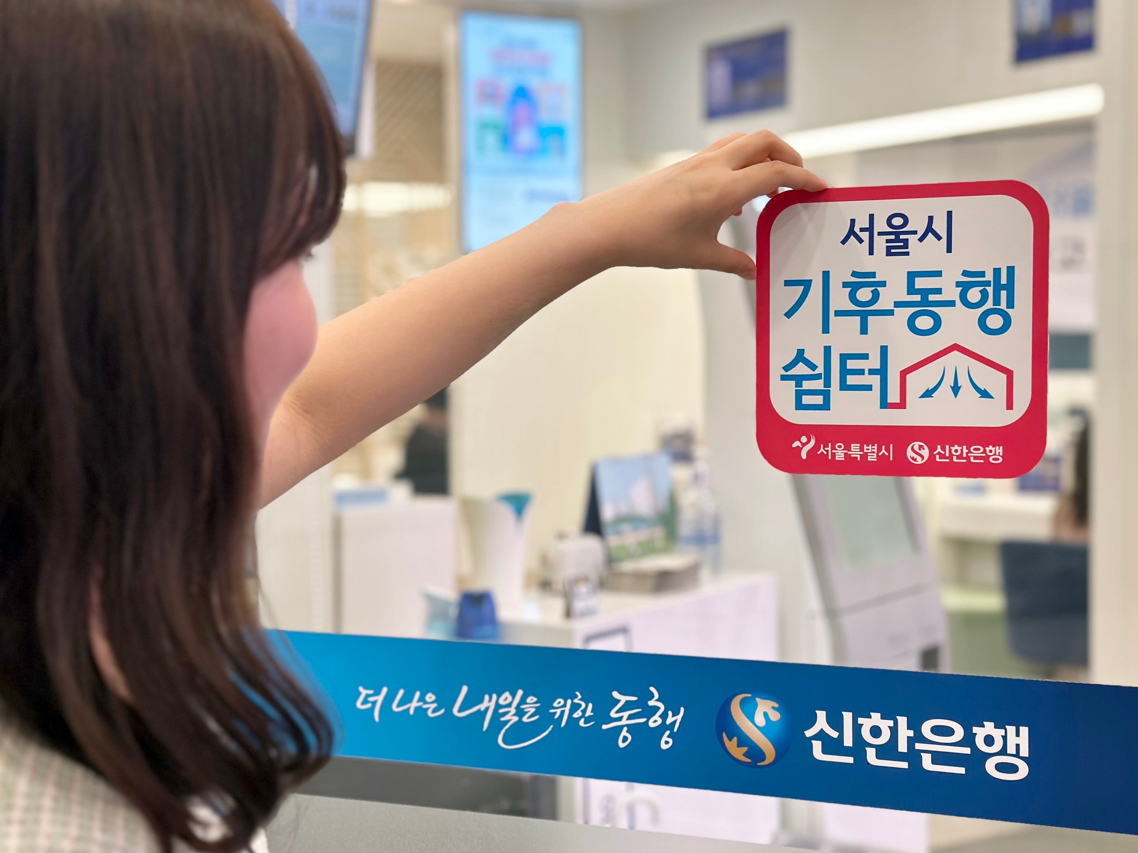 신한은행 시청점 입구에 기후동행쉼터 안내 현판을 붙이는 모습 (서울시 제공)