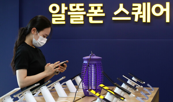 한 시민이 2022년 6월 21일 서울 시내에 위치한 알뜰폰 스퀘어 매장에서 휴대폰을 만지고 있다. / 뉴스1