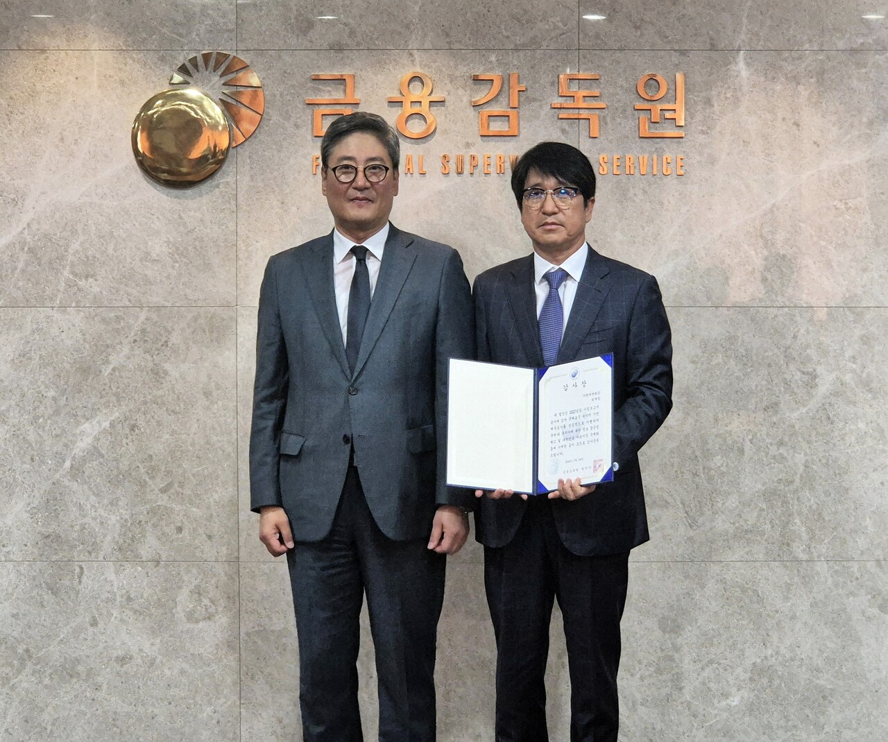 민왕일 현대백화점 경영지원본부 부사장(오른쪽)이 금융감독원으로부터 XBRL 재무 공시 우수법인 감사장을 수여받은 뒤 김정태 금융감독원 공시조사 부원장보와 기념사진을 촬영하고 있다. / 현대백화점그룹