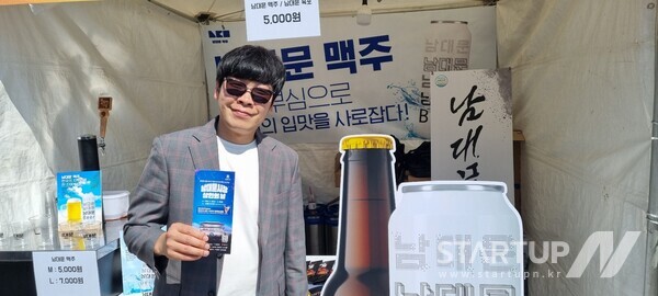 새롭게 출시된 남대문 맥주 부스 앞에서 가수겸 배우 백봉기씨가 포즈를 취하고 있다.