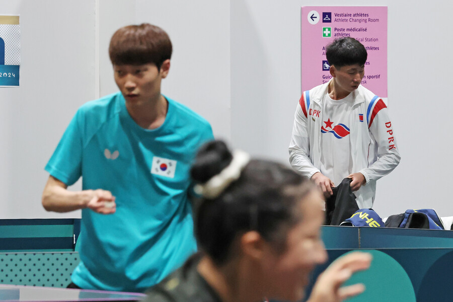 ▲ 22일(현지시간) 프랑스 파리 사우스 파리 아레나4에 마련된 탁구 경기장에서 훈련 중인 신유빈과 조대성 뒤로 북한 대표팀 리종식이 연습 준비를 하고 있다. ⓒ연합뉴스