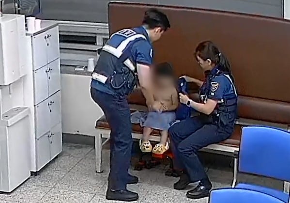 오후 10시에 기저귀만 찬 채 떠돌던 A군에게 근무복 입혀주는 경찰./연합뉴스