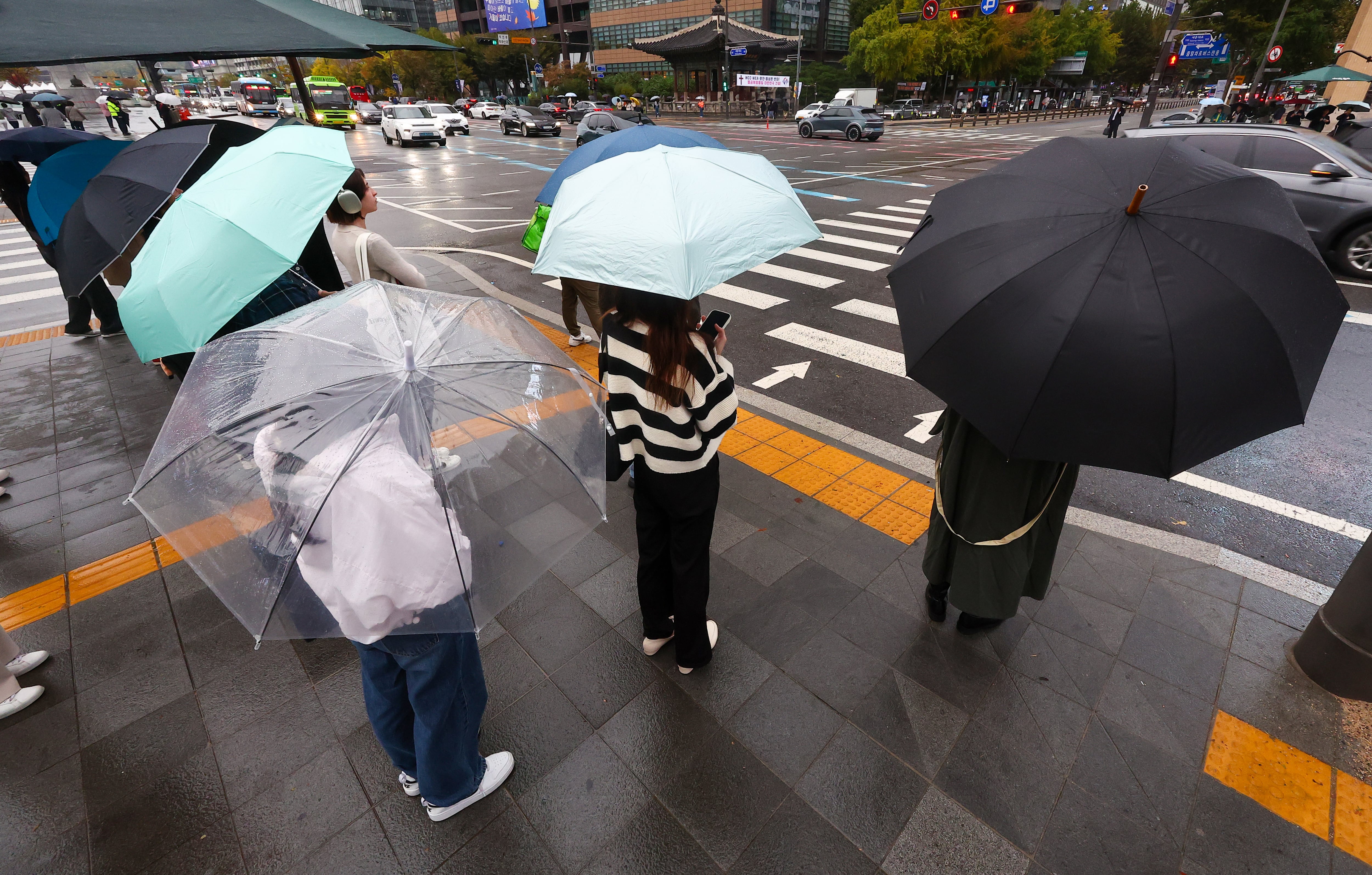 22일 오전 서울 종로구 광화문사거리에서 시민들이 우산을 쓰고 출근하고 있다. /연합뉴스