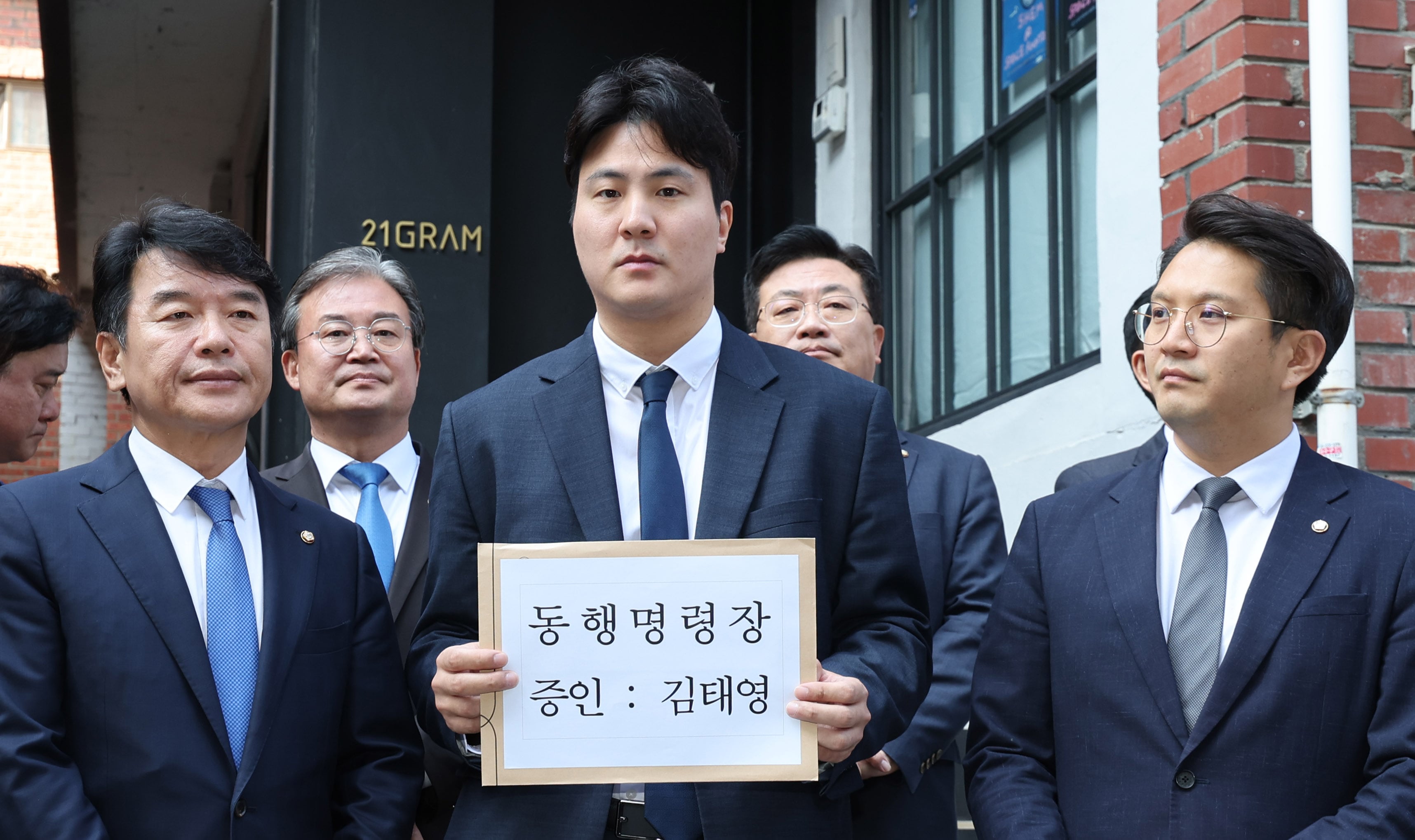국회 행정관이 24일 오후 서울 성동구 21그램 사무실 앞에서 대통령 관저 불법증축 관련 김태영 21그램 대표 동행명령장을 들고 있다. 대통령 관저 불법 증축 핵심 업체인 21그램 김태영 대표에 대해 이날 국회는 동행명령장을 발부했다. /뉴스1