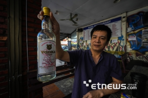 지난 19일(현지시간) 라오스 방비엥의 한 호스텔 매니저가 이 곳에서 파는 보드카를 들어보이고 있다. 이 호스텔에 투숙한 호주 여성 2명이 메탄올 중독 증상을 보여 1명이 숨지고 1명은 중태다.〈사진=연합뉴스〉