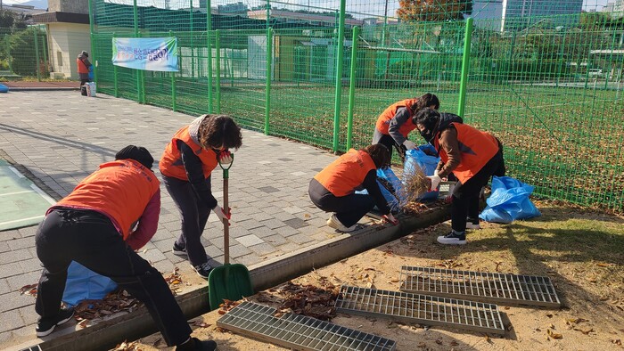 ‘반송 쓰담달리기’에 참여한 성산구 반송동 주민들이 운동장 배수로를 정비하고 있다.(사진=창원시)