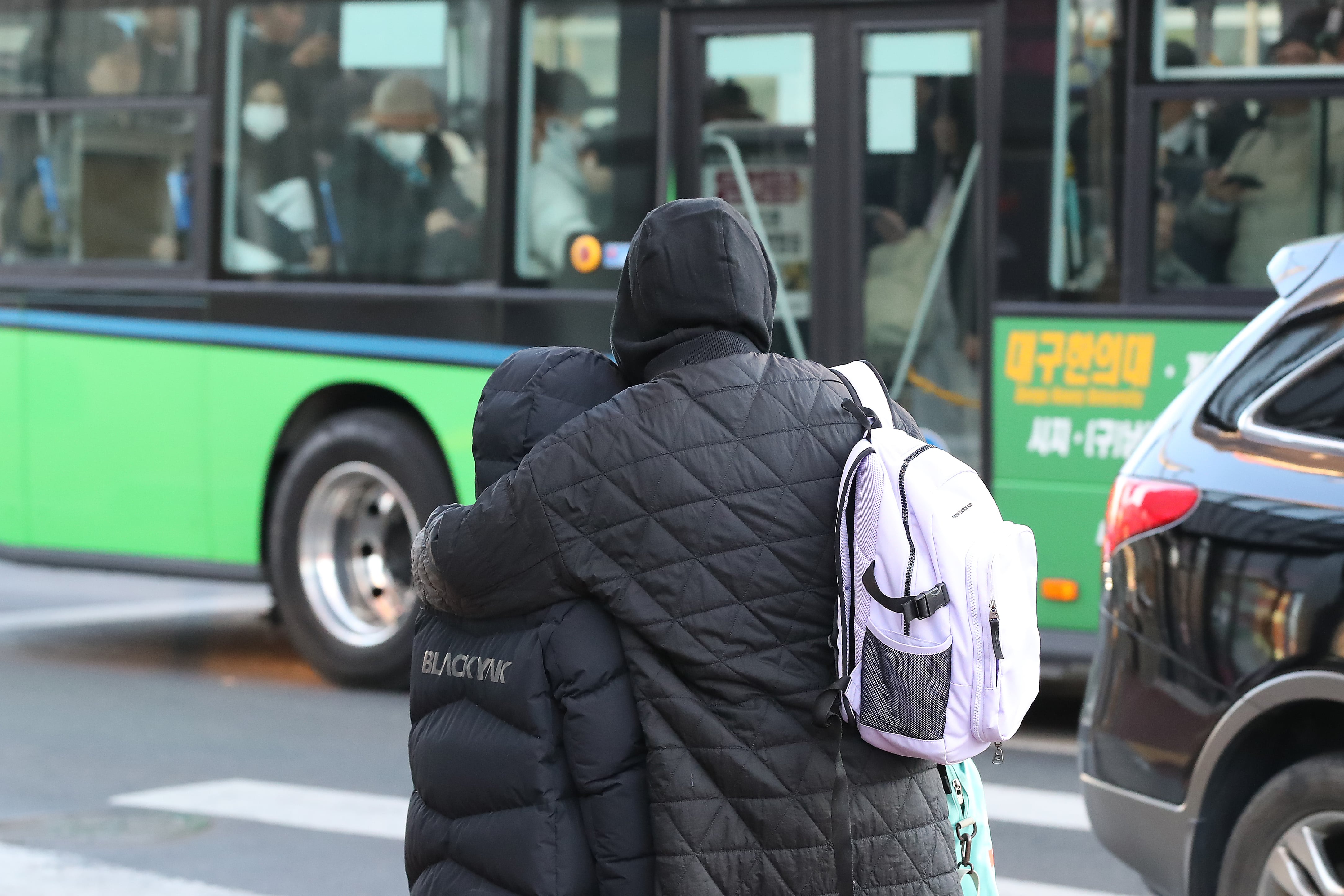 두꺼운 외투를 챙겨 입은 학생과 엄마가 꼭 끌어안은 채 보행자 신호를 기다리고 있다. /뉴스1