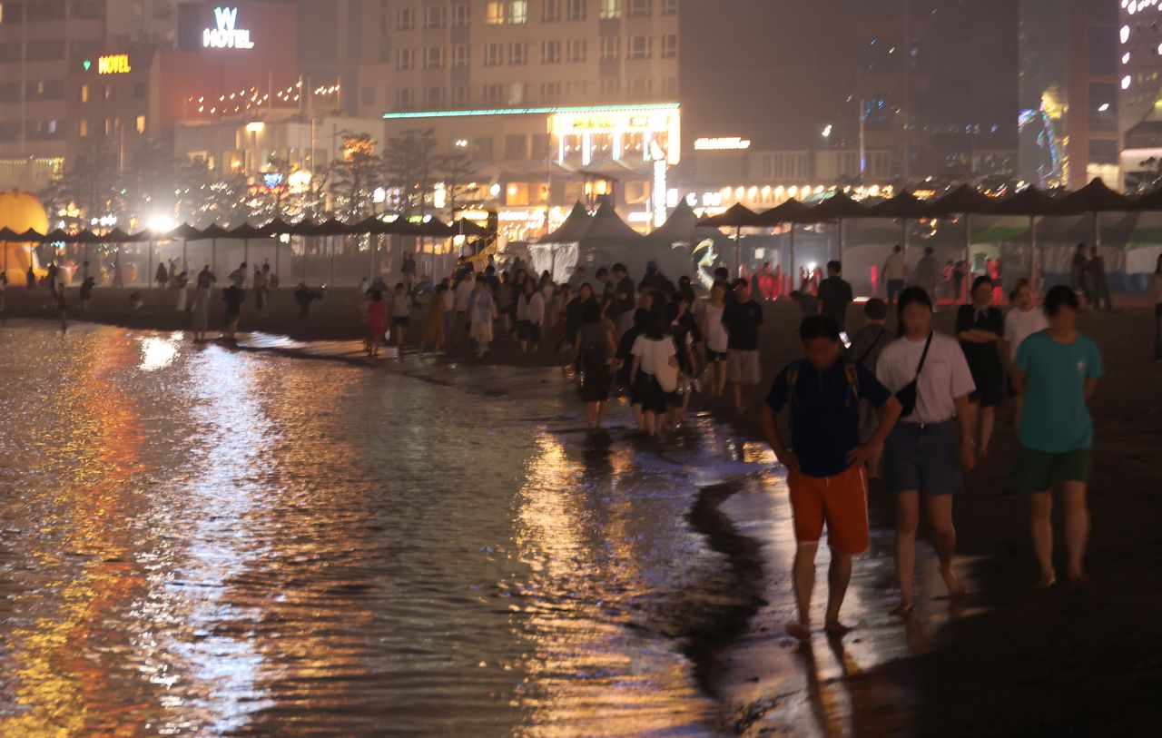 People walk along Gwangalli Beach in Busan, southeastern South Korea, on Monday, amid the prolonged heat wave and tropical night. (Yonhap)