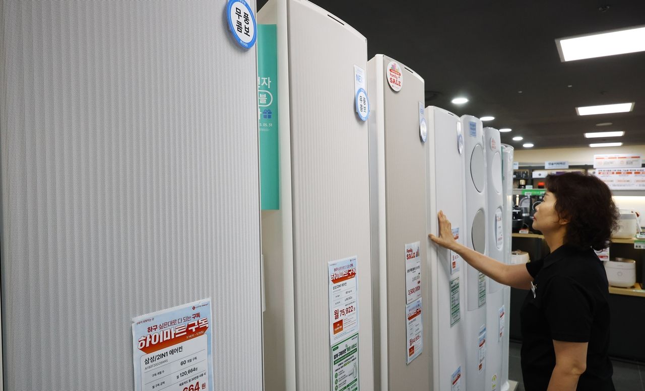 As South Korea braces for a severe summer heat wave, an employee at Lotte Hi-Mart, a local electronics retailer, checks air conditioning units at a Seoul branch on May 26. (Newsis)
