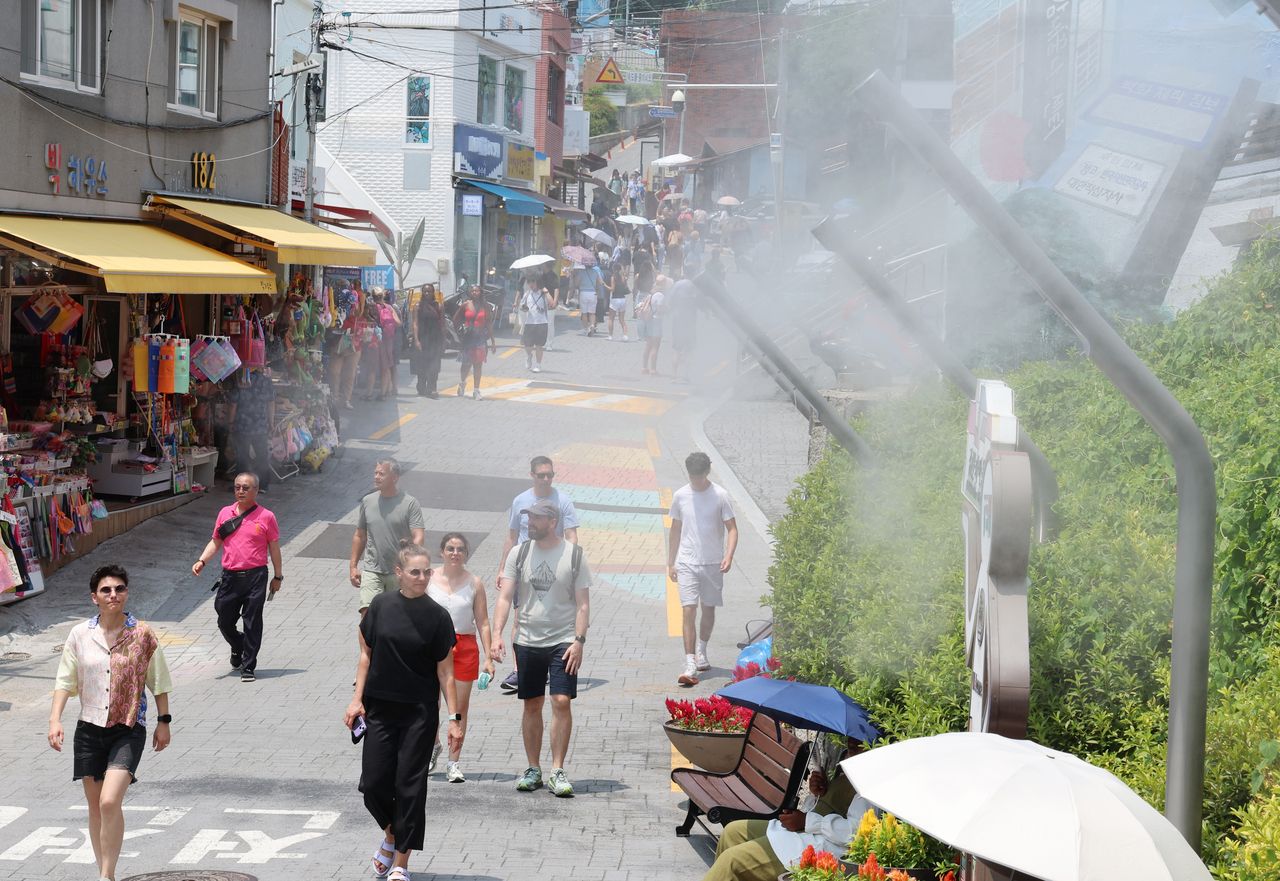 Foreign visitors cool off in sweltering weather in the southeastern port city of Busan on Tuesday, as most parts of the country remain under extreme heat warnings or advisories. (Yonhap)]