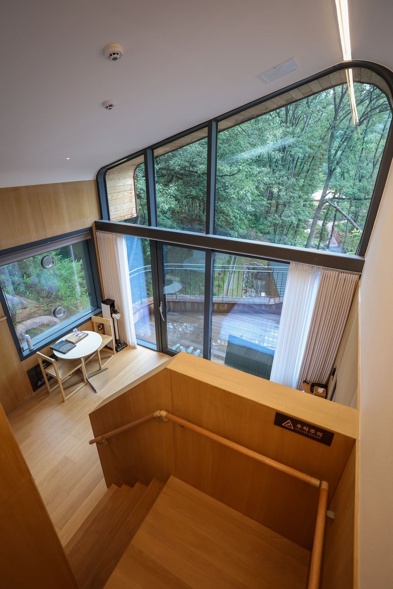 Natural light fills a two-story treehouse unit at Surak Hue, where full-length windows look directly into the forest. (Nowon-gu Office)