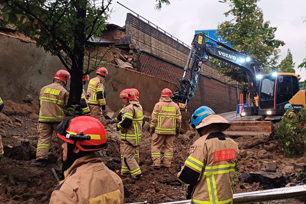 Rescue workers try to uncover a collapse of a retaining wall in Osan, Gyeonggi Province, Wednesday. (Gyeonggi Fire and Disaster Headquarters)]