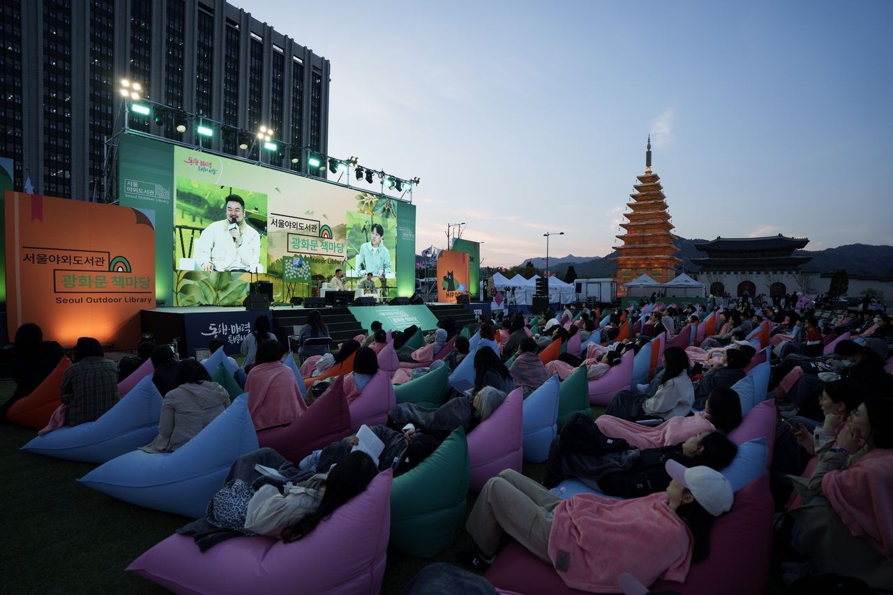 Author Park Sang-young speaks to a full crowd at the Seoul Outdoor Library's Hip Dok Club event in Gwanghwamun Square. He shared behind-the-scenes stories from writing