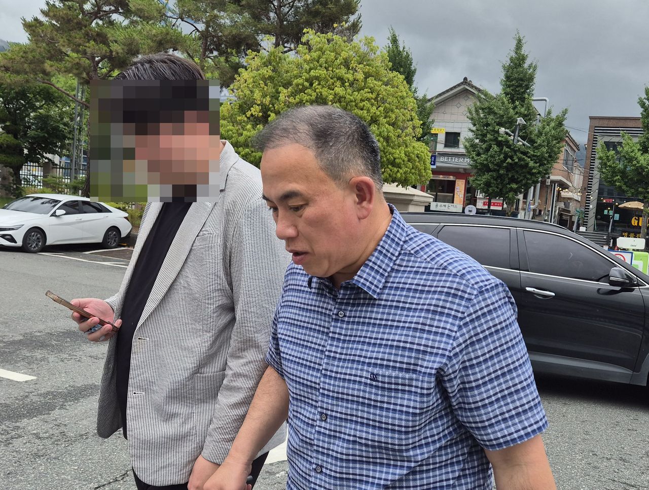 Myung Tae-kyun (right) arrives at the Changwon Jungbu Police Station in Changwon, South Gyeongsang Province, on June 20. (Yonhap)]
