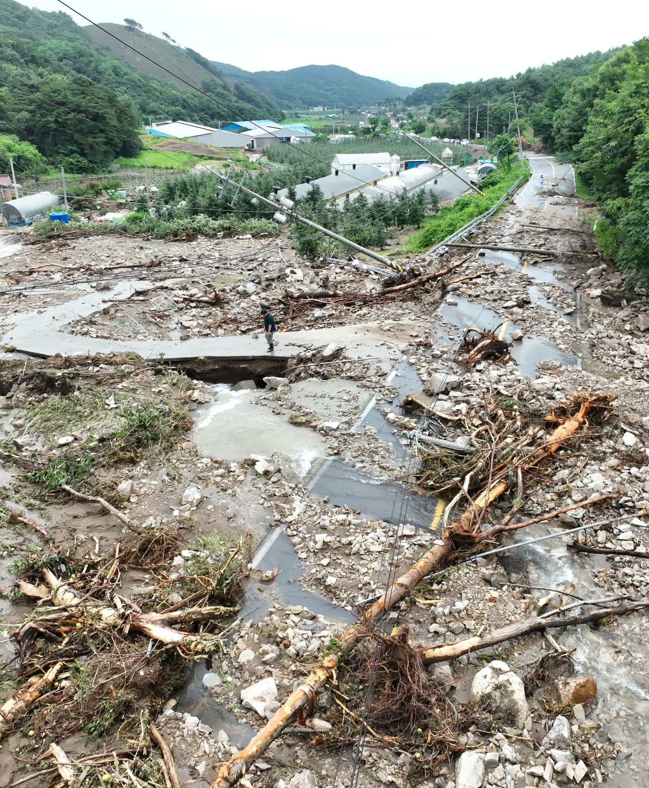 A road is covered with earth and rocks brought by a nearby landslide in a village in Yesan, South Chungcheong Province, central South Korea, on Thursday following torrential rains that hit the region. (Yonhap)]