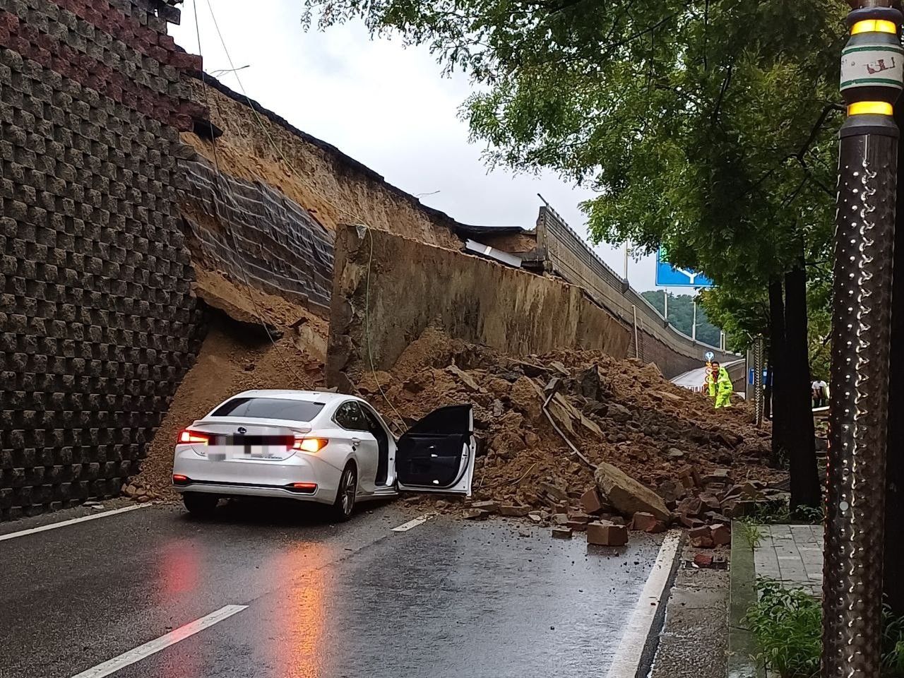 This photo distributed by the rescue authorities in Gyeonggi Province shows a collapsed retaining wall on the side of a road in Osan, Gyeonggi Province, on Wednesday. (Yonhap)]