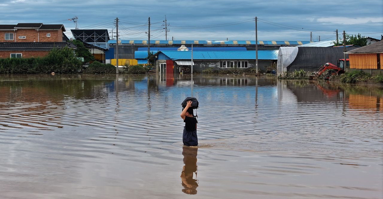 A resident of Yesan-gun, South Chungcheong Province escapes a flooded village carrying a bag on Friday after more than 400 millimeters of rain fell on North and South Chungcheong provinces. (Im Se-jun/The Korea Herald)