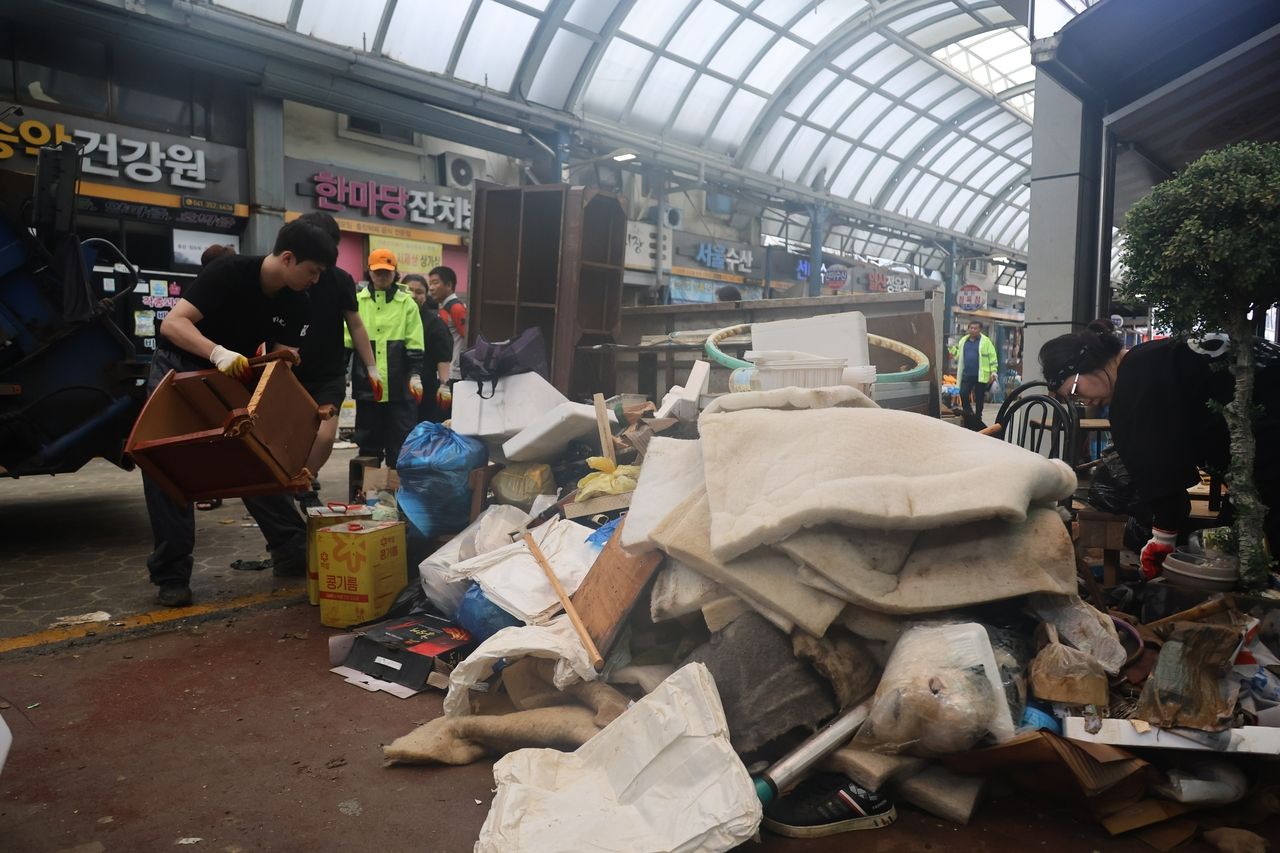 Piles of soaked furniture and waste are removed from shops in Dangjin’s traditional market on Friday after torrential rains flooded the area. (Yonhap)