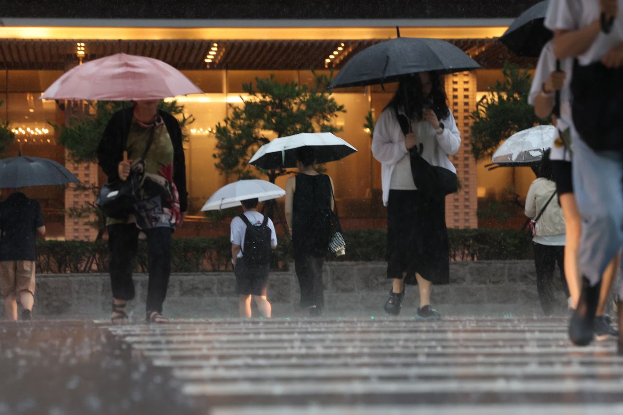Commuters head to work through heavy rain and thunderstorms in Mapo-gu, Seoul, on July 17. (Yonhap)