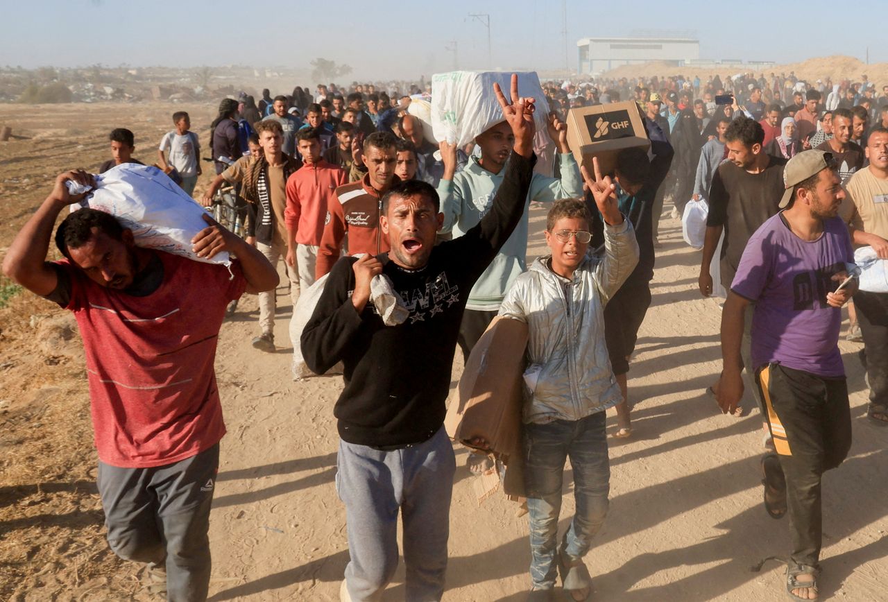 Palestinians carry aid supplies from the US-backed Gaza Humanitarian Foundation, in Khan Younis, Gaza Strip, in May. (Reuters-Yonhap)]