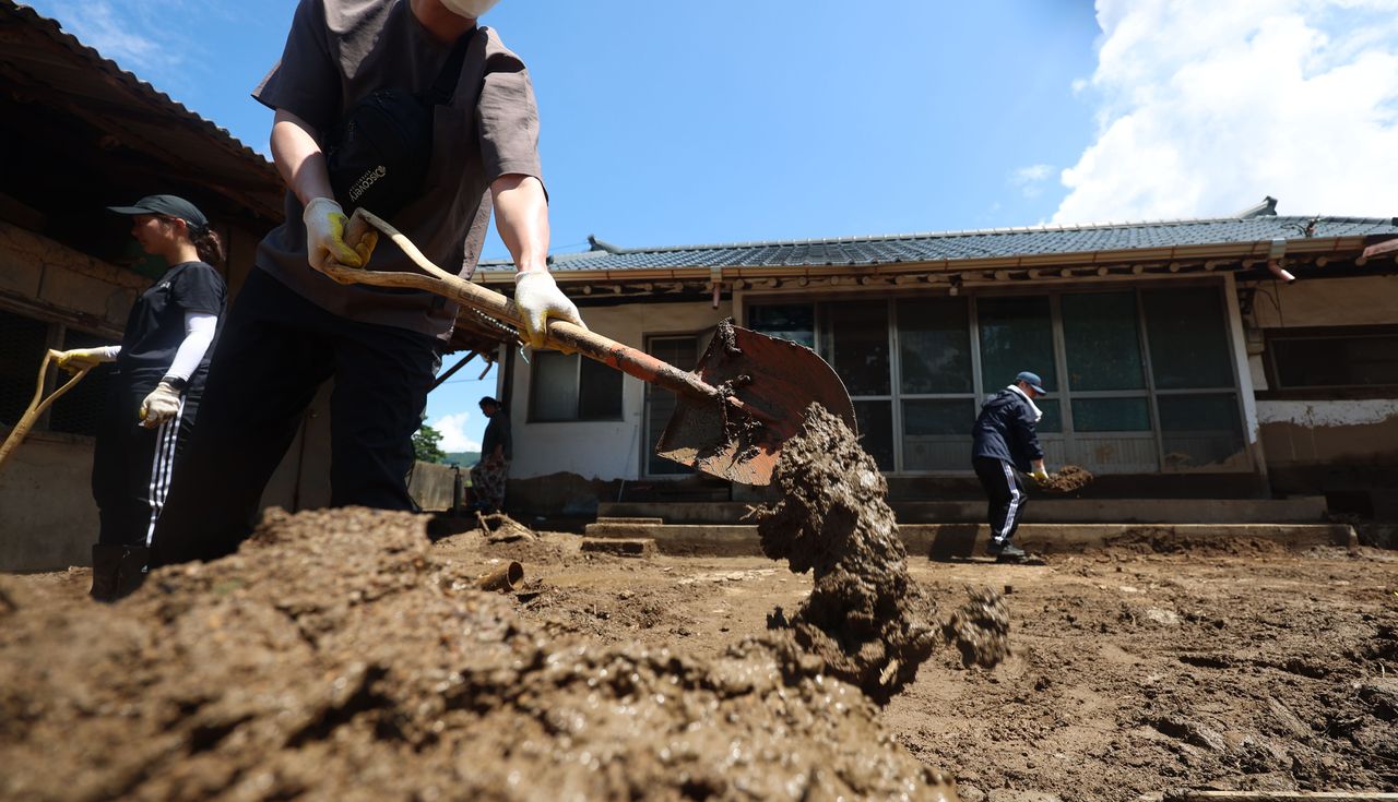 Public officials work to recover a house in a flood-damaged village in Sancheong, South Gyeongsang Province, Tuesday. (Yonhap)]
