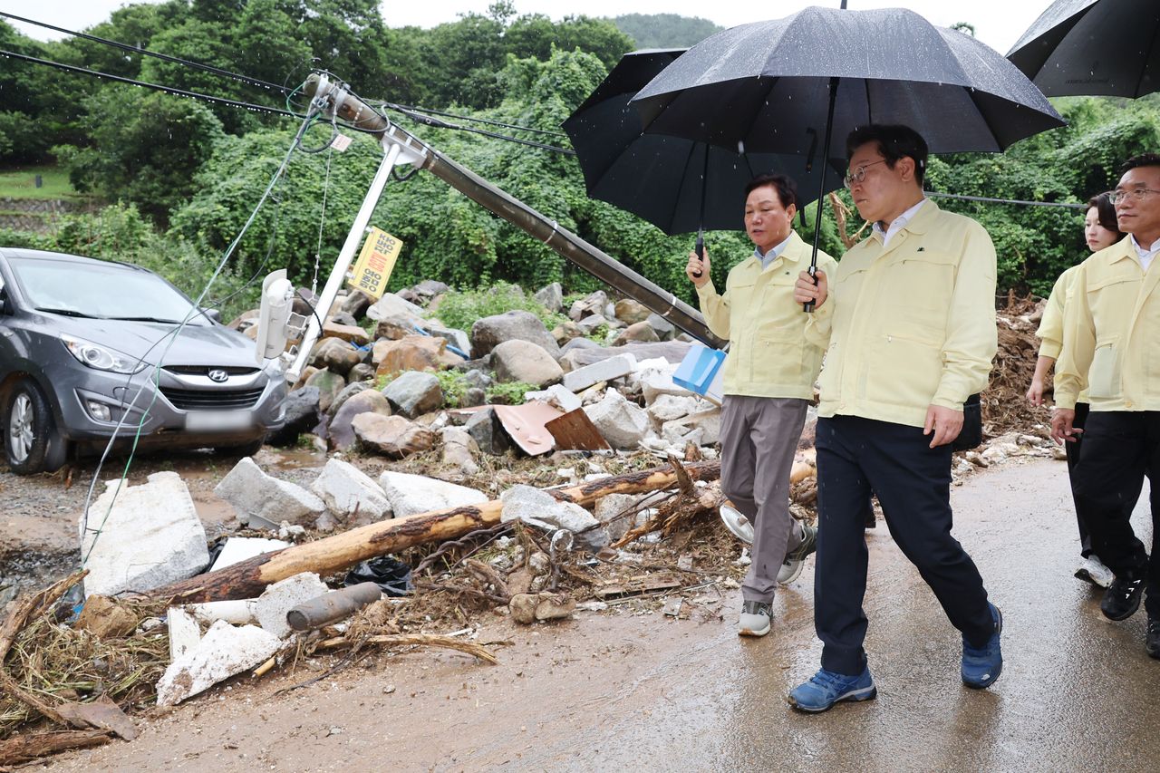 President Lee Jae Myung (second from left) visits a flood-damaged village in Sancheong, South Gyeongsang Province, Monday. (Yonhap)]