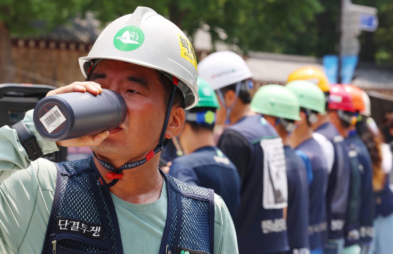 A worker drinks water during a press conference held by the construction workers]
