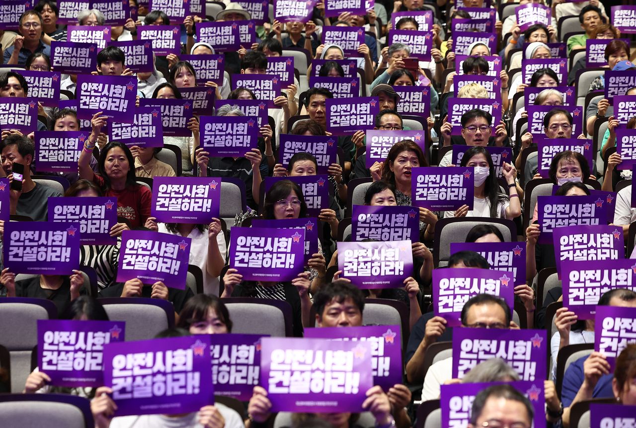 Bereaved family members of the victims of the 2022 Itaewon crowd crush hold signs reading]