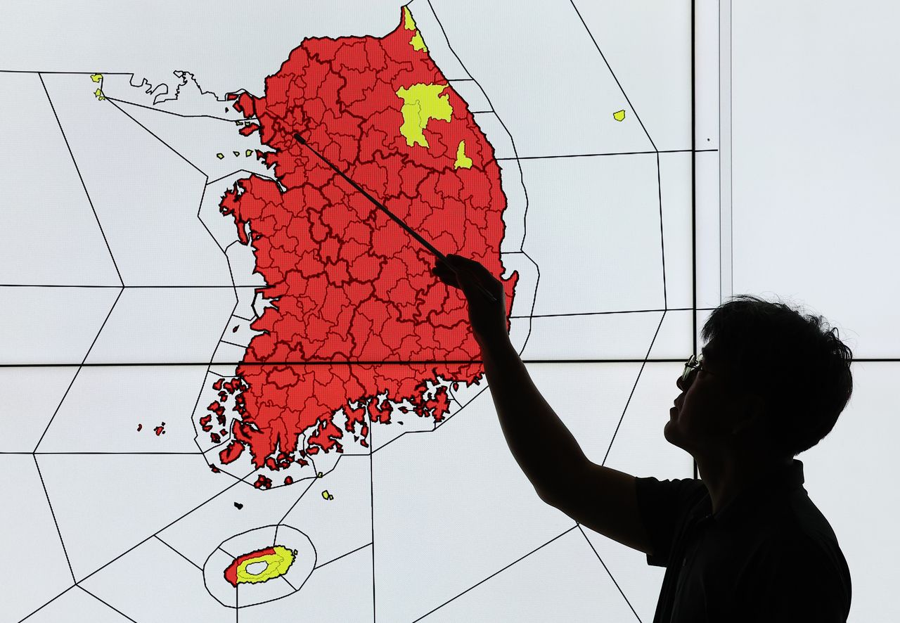 An official from the Korea Meteorological Administration monitors South Korea's status of issued heat waves at the KMA headquarters in Dongjak-gu, southern Seoul on Wednesday. The areas marked in red indicate areas issued with a heat wave warning, while those in yellow indicate areas with a heat wave advisory in effect. (Yonhap)