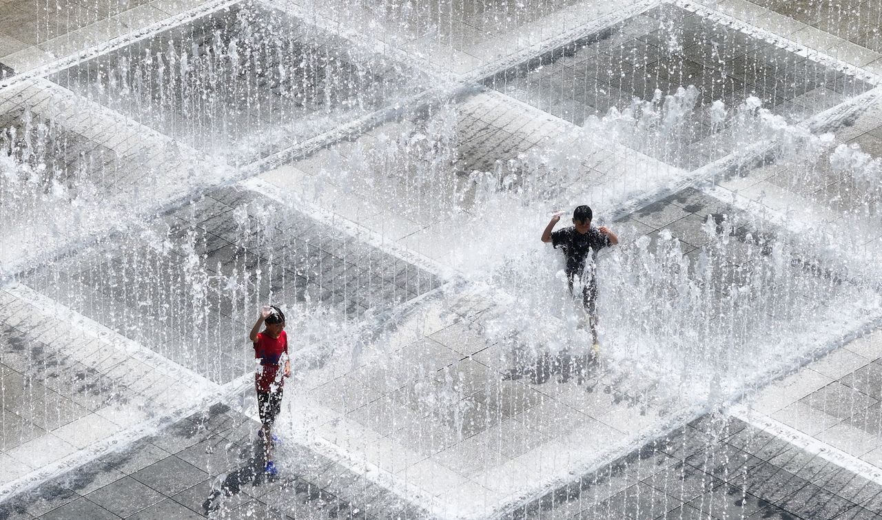 Children cool off by playing in the water at a floor fountain installed in Pyeongri Park in Daegu, Monday. (Yonhap)]