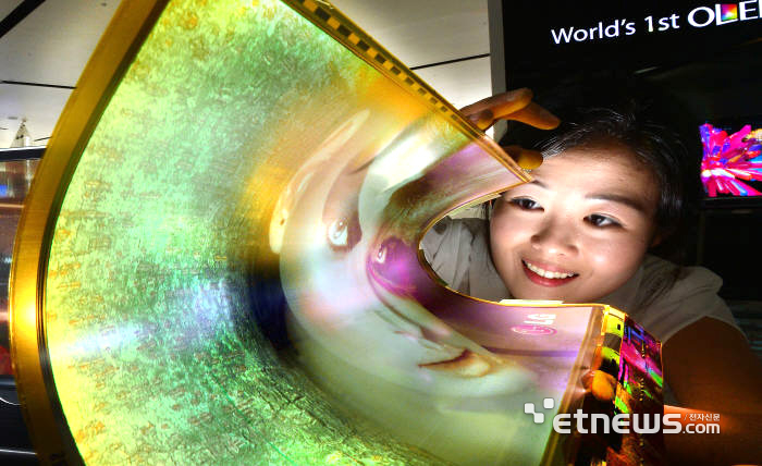 접고 구부릴 수 있는 플렉시블 디스플레이 시대가 도래했다. 웨어러블 기기 등 사물인터넷(IoT) 기반 융합 제품 혁신에 중요한 역할을 담당할 것으로 예상된다. LG디스플레이 직원이 최근 개발에 성공한 곡률반경도 30R을 구현하는 18인치 플렉시블 OLED를 보여주고 있다.  김동욱기자 gphoto@etnews.com