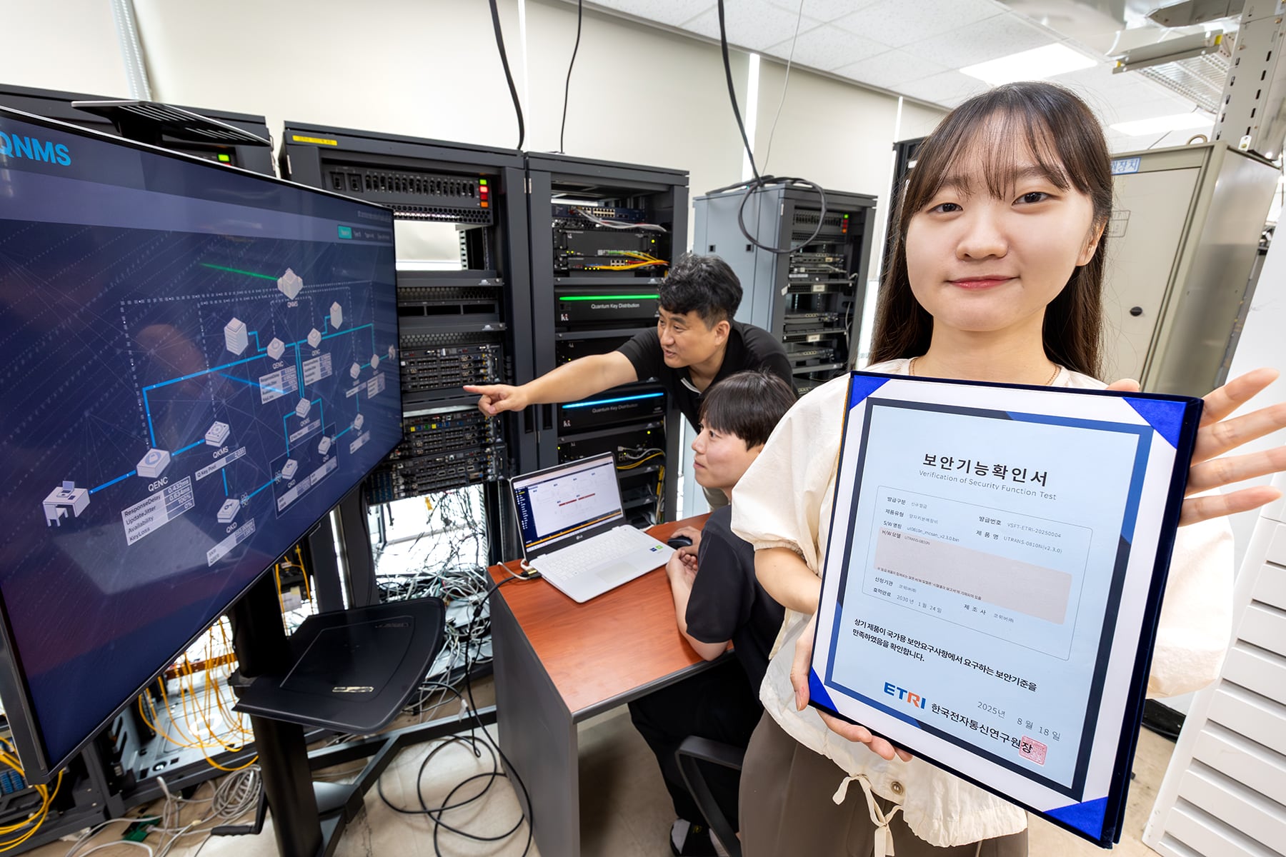 KT와 코위버 직원이 양자키분배 기술 적용 장비를 점검하며 보안 인증서를 소개하고 있다./KT 제공