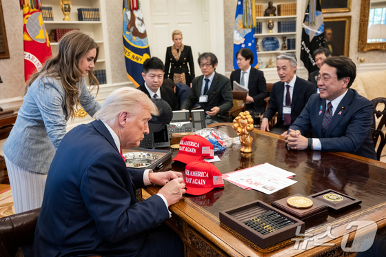 On July 16, U.S. President Donald Trump signed his Make America Great Again (MAGA) hat before tariff negotiations with Japanese Minister for Economic Revitalization Ryosei Akazawa in the Oval Office at the White House in Washington, D.C. (Provided by the White House) / News1