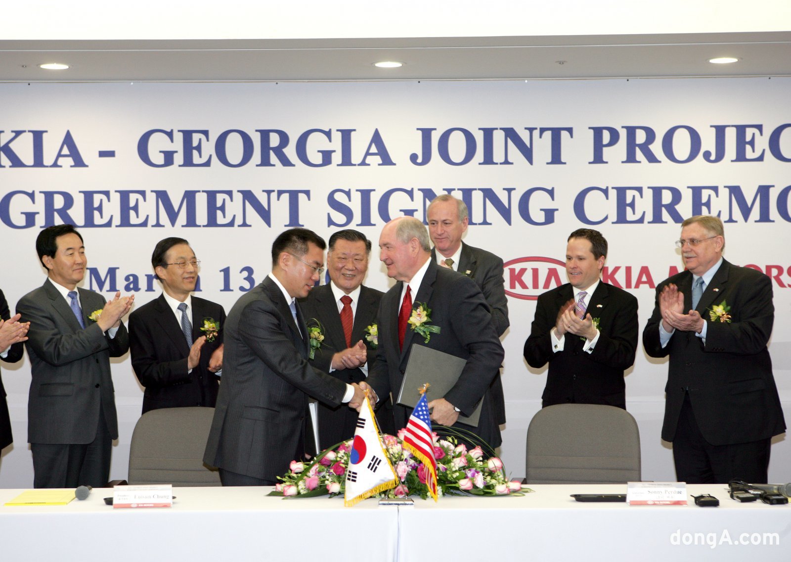 2006년 기아 조지아공장 투자계약식에서 정몽구 명예회장이 지켜보는 가운데 정의선 회장과 소니 퍼듀 조지아 주지사가 투자 계약서에 서명한 후 악수하고 있다.