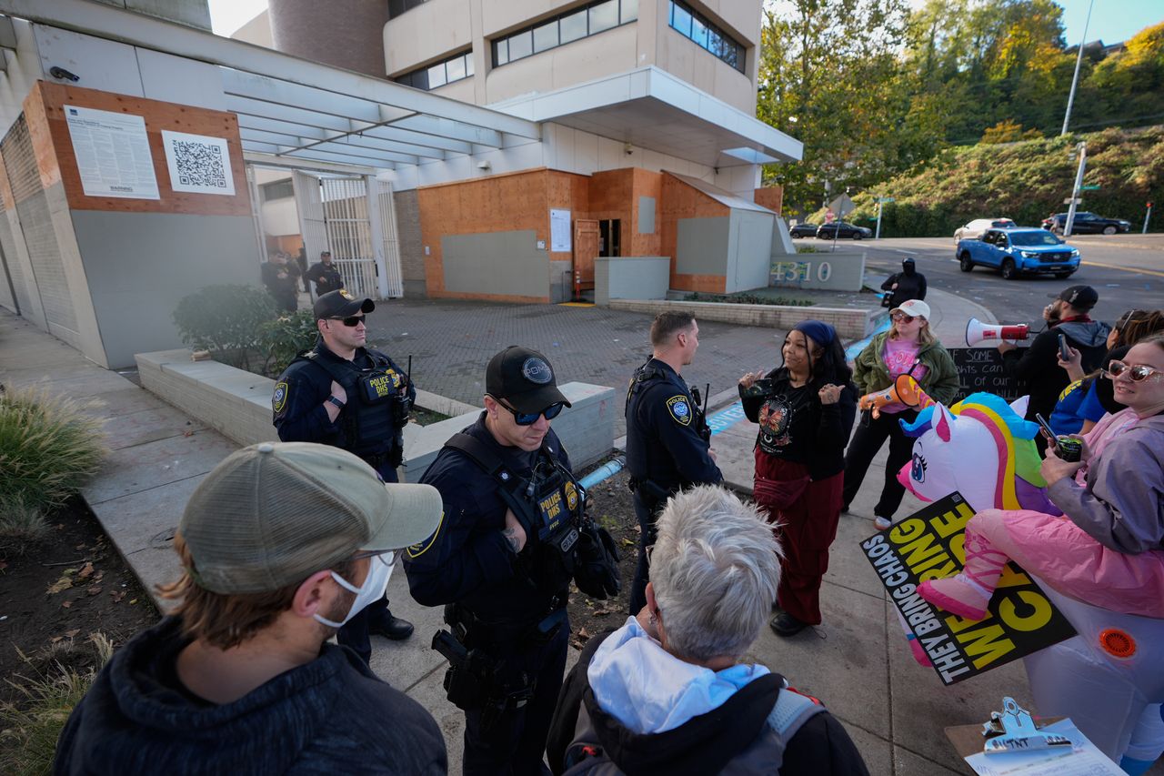 Law enforcement officers talk with protesters outside an Immigration and Customs Enforcement facility in Portland, Monday. (AP-Yonhap)