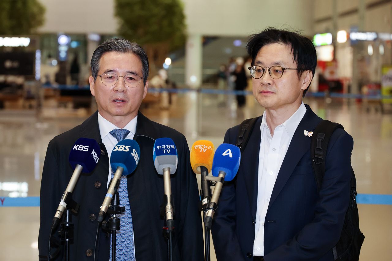Kim Yong-beom (L), presidential chief of staff for policy, and Industry Minister Kim Jung-kwan speak to reporters at Incheon International Airport on Friday. (Yonhap)