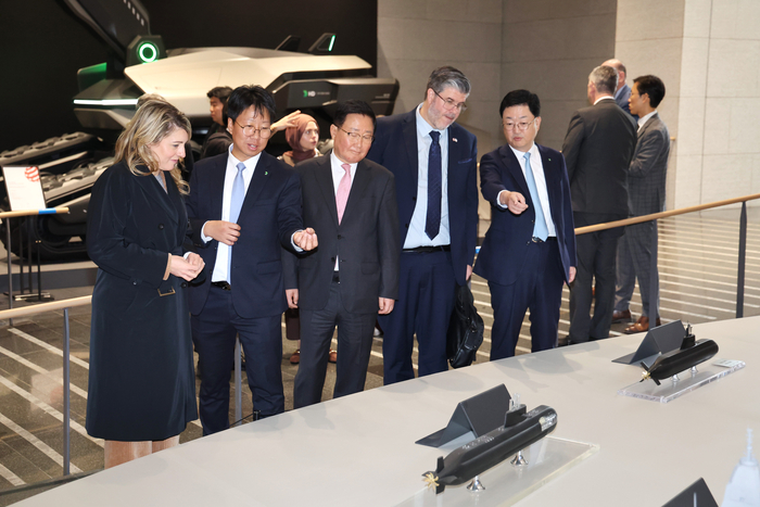 멜라니 졸리 캐나다 산업부 장관과 필립 라포튠 주한 캐나다 대사 일행이 HD현대 조석 부회장, HD현대중공업 주원호 사장과 함께 HD현대 글로벌R&D센터에서 미래형 선박·잠수함·호위함 등 함정 모형을 둘러보고 있다. HD현대
