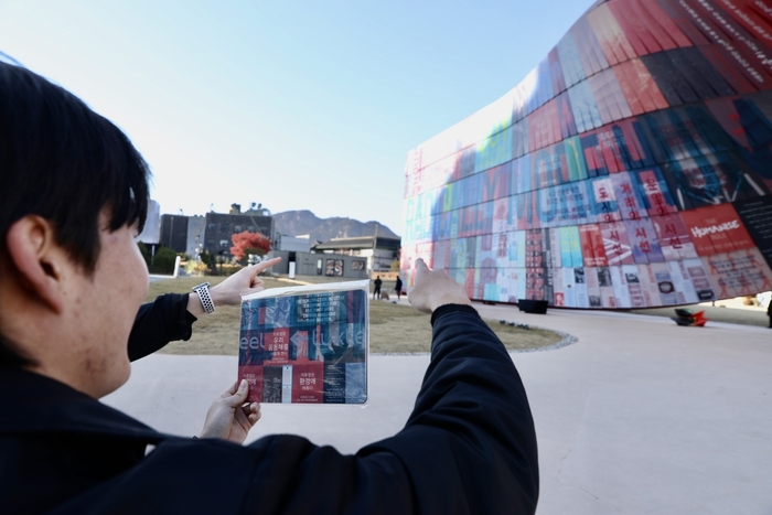시민이 휴머나이즈 월에서 마우스패드에 인쇄된 부분을 찾아 기념사진을 찍고 있는 모습. 동국홀딩스