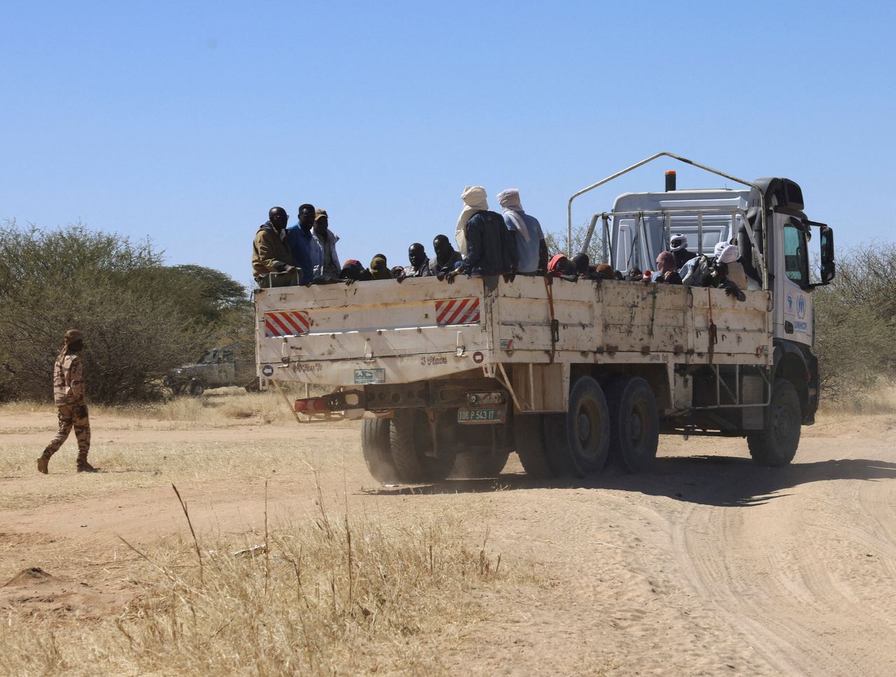 A member of the Chadian army walks next to Sudanese refugees from al-Fashir as they are transported by UNHCR from Tine to the Tuloum refugee camp, in eastern Chad, Friday. (Reuters-Yonhap)