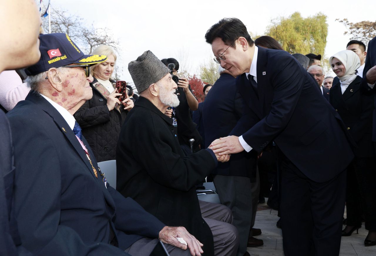 President Lee Jae Myung (right) shakes hands with a Turkish veteran after paying tribute at the Korean War Memorial in Korean Park in Ankara on Tuesday.(Yonhap)