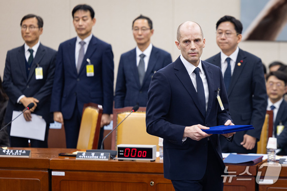 Harold Rogers, Coupang\'s interim CEO, moves to hand over his oath of testimony to Choi Min-hee, chairperson of the National Assembly\'s Science, Information and Communications Technology (ICT), Broadcasting, and Communications Committee, after completing his oath at a hearing regarding the Coupang personal information leak incident held at the committee in Yeouido, Seoul, on Wednesday. 2025.12.17 / News1