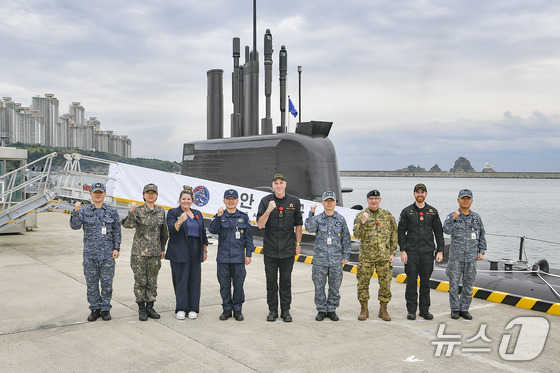 On October 31, Canadian Navy Commander Angus Topshee (center), accompanied by South Korean Submarine Commander Kang Dong-gu (left) and other naval officials from both nations, poses for a commemorative photo in front of a Dosan Ahn Chang-ho-class submarine during their visit to the Busan Naval Base. (Photo provided by the Republic of Korea Navy) 2025.10.31 / News1