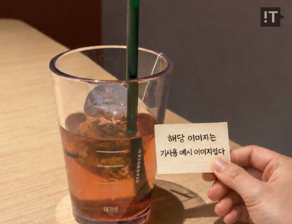 실제 음료 사진에 “메모지를 들고 있는 손을 추가해 줘. 컵 앞에 위치한 메모지에는 ‘해당 이미지는 기사용 예시 이미지입니다’라는 멘트를 추가해줘. 사진 속에 있는 그림자를 고려해서 손과 메모지 그림자도 자연스럽게 생성해 줘”라는 프롬프트를 통해 수정한 버전 / AI를 통해 생성한 이미지