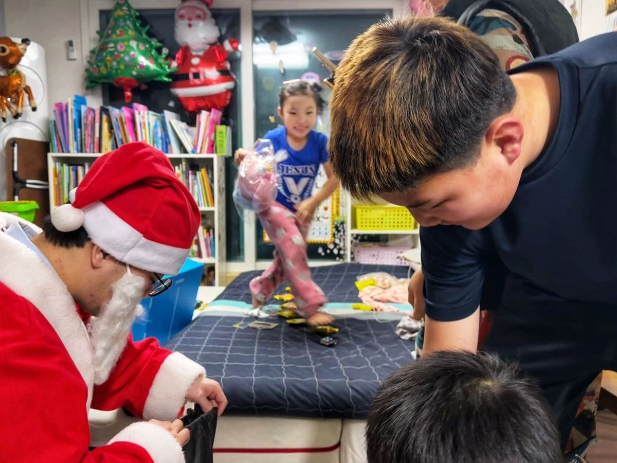 This photo shows children receiving Christmas presents, from a volunteer worker dressed up as Santa Claus on Wednesday. (Yonhap)